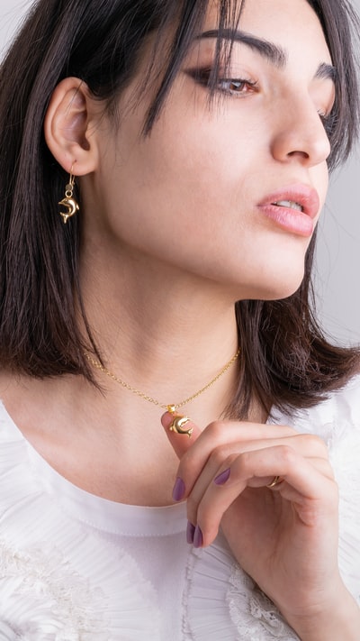 A woman of gold necklace in white shirt
